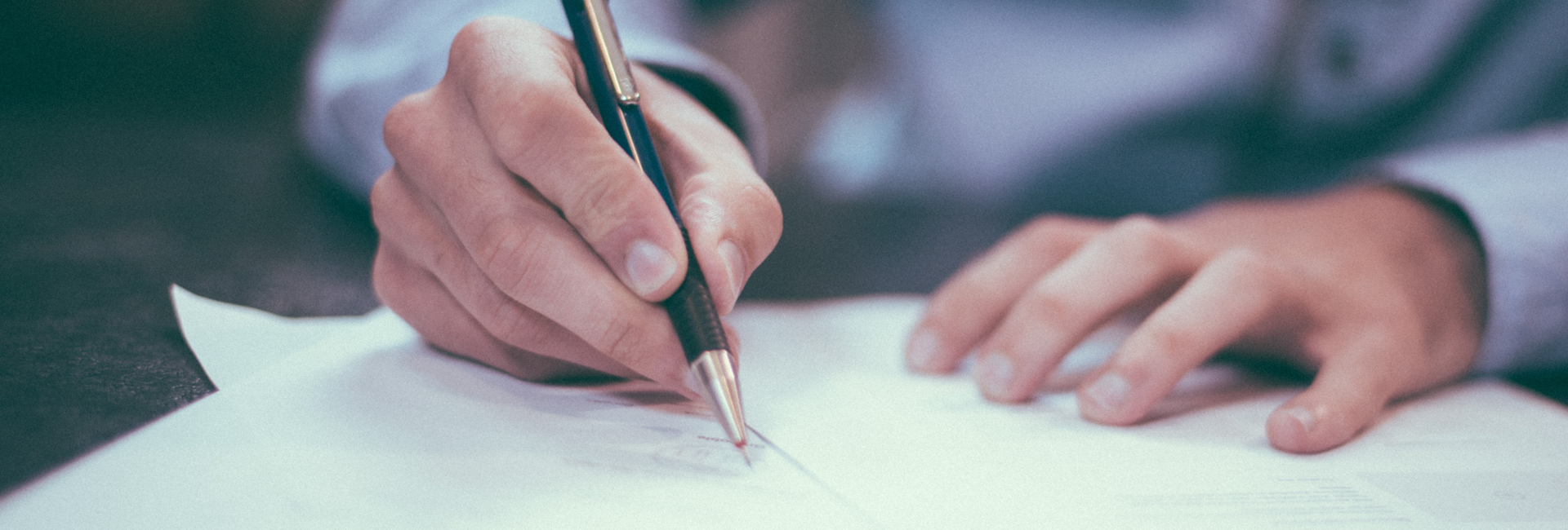 close up of someone wearing a shirt wrting on some papers